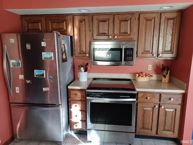 kitchen with stainless steel appliances, light countertops, brown cabinets, and light tile patterned floors