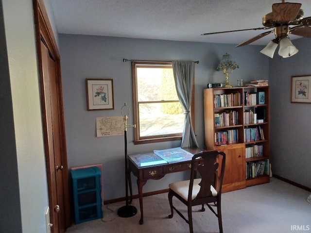 carpeted home office with baseboards and a ceiling fan