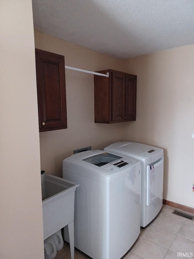 laundry area featuring cabinet space, baseboards, visible vents, washing machine and clothes dryer, and a textured ceiling