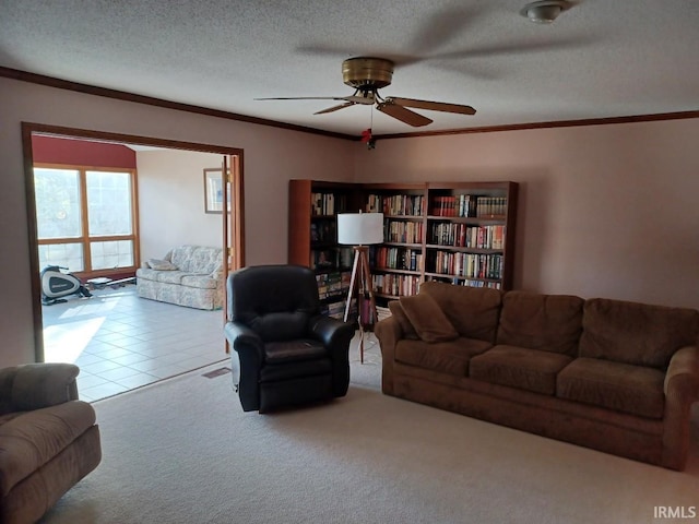 carpeted living area featuring ceiling fan, ornamental molding, a textured ceiling, and tile patterned floors