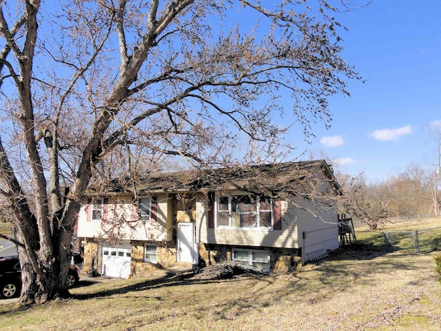 bi-level home featuring an attached garage, fence, and a front yard