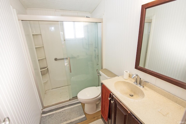 bathroom featuring toilet, a stall shower, and vanity