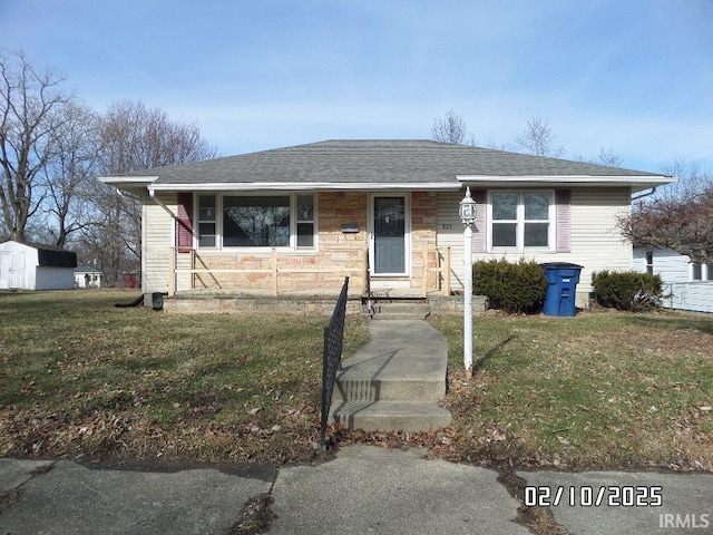 view of front of home with stone siding, a front lawn, and a shingled roof