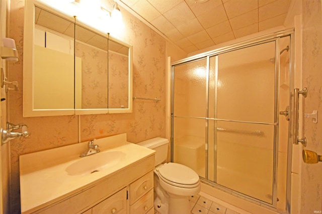 bathroom with vanity, a shower stall, toilet, and wallpapered walls