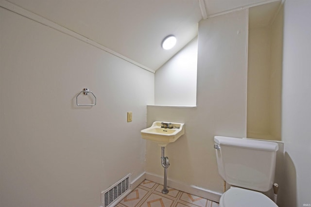 bathroom with toilet, lofted ceiling, visible vents, and baseboards