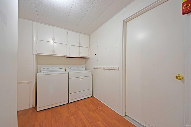 laundry room with separate washer and dryer, cabinet space, and light wood-style floors