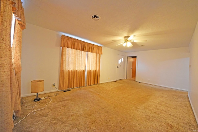 carpeted empty room featuring visible vents, a ceiling fan, and baseboards