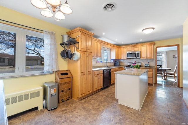 kitchen featuring visible vents, decorative backsplash, radiator heating unit, a center island, and stainless steel appliances