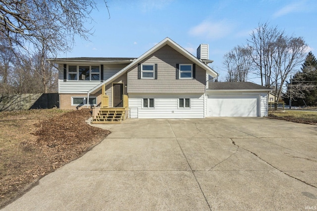 bi-level home featuring driveway, a chimney, and fence