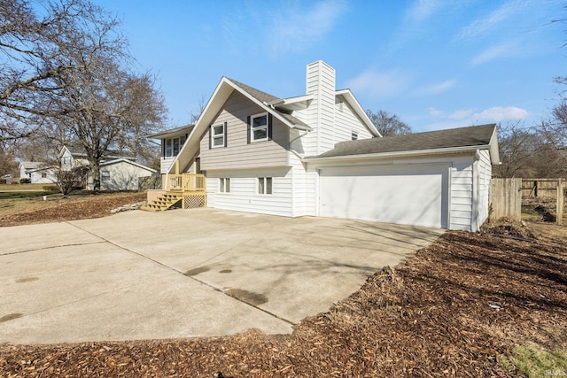 view of property exterior featuring driveway, a chimney, an attached garage, and fence