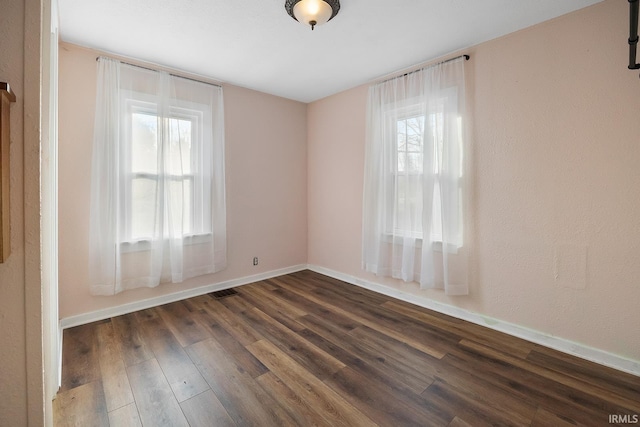 empty room featuring dark wood finished floors and baseboards