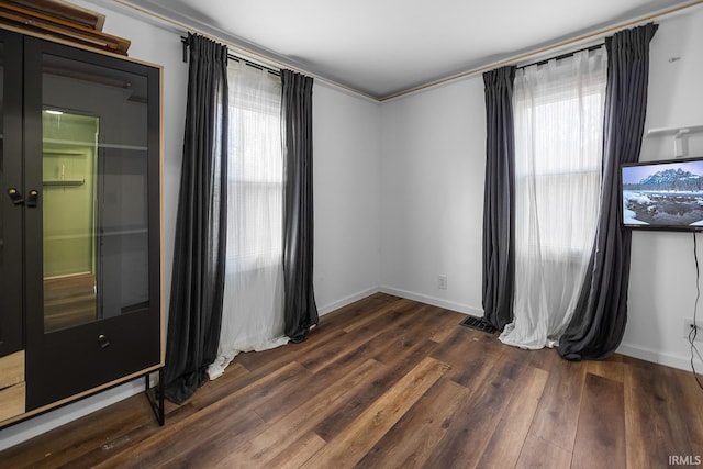 empty room featuring plenty of natural light, baseboards, and wood finished floors