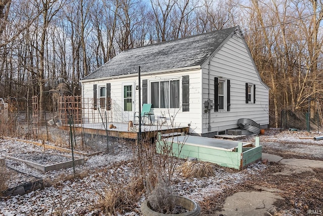 view of front facade featuring a garden, a wooden deck, and roof with shingles