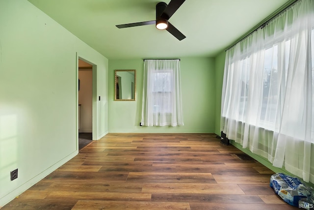 empty room featuring dark wood-style floors, baseboards, and a ceiling fan