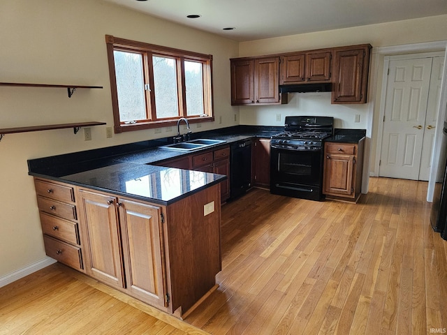 kitchen featuring black appliances, dark countertops, a sink, and a peninsula