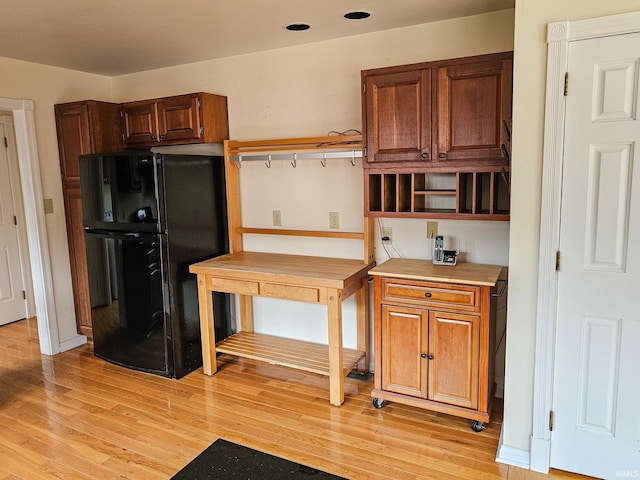 kitchen featuring light wood finished floors, open shelves, light countertops, and freestanding refrigerator