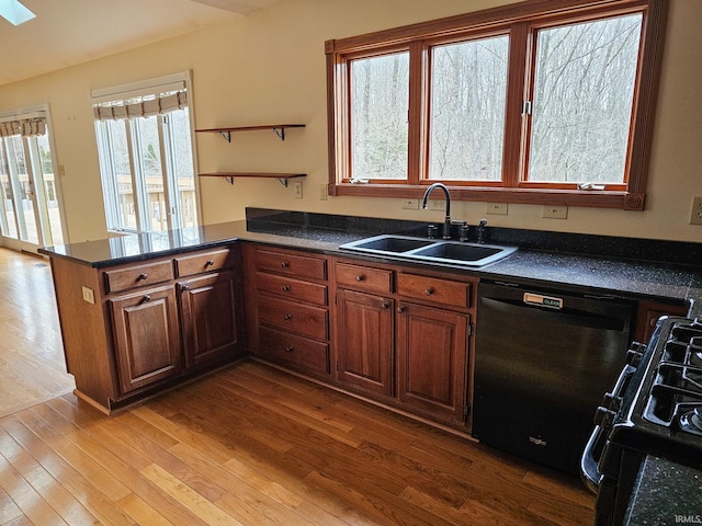 kitchen featuring dishwasher, dark countertops, a sink, and range with gas cooktop