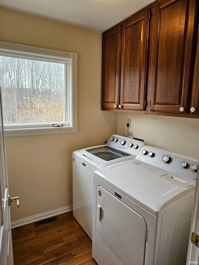 laundry area featuring wood finished floors, visible vents, baseboards, cabinet space, and washing machine and clothes dryer