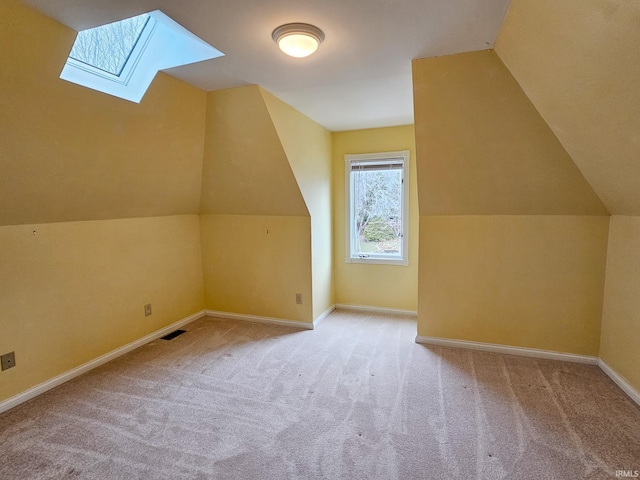 additional living space with lofted ceiling with skylight, carpet, visible vents, and baseboards