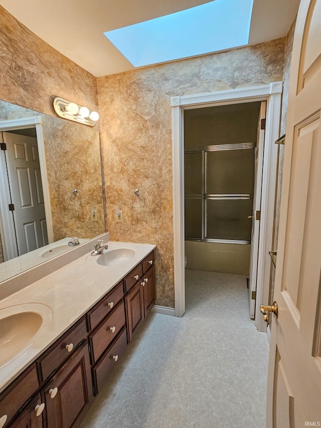 bathroom featuring double vanity, a skylight, and a sink