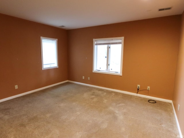 carpeted spare room featuring visible vents and baseboards