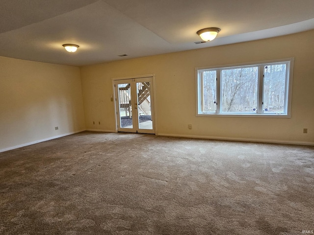 empty room featuring a healthy amount of sunlight, carpet, baseboards, and french doors