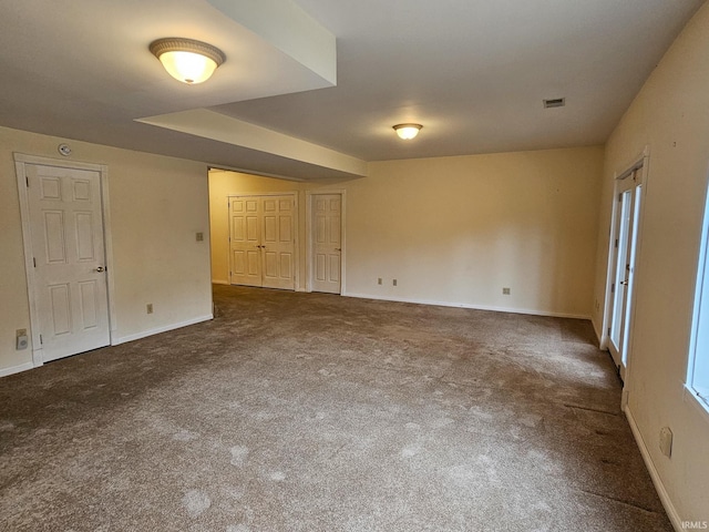 empty room featuring carpet, visible vents, and baseboards