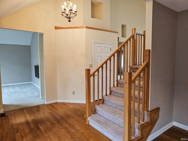 stairs featuring baseboards, high vaulted ceiling, wood finished floors, and a notable chandelier