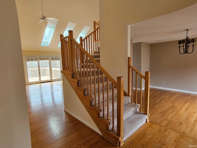 stairway with high vaulted ceiling, a skylight, baseboards, and wood finished floors