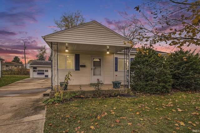 view of front of home featuring an outbuilding, a yard, a porch, and a garage