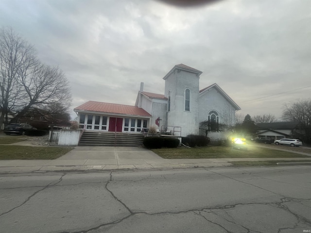 view of front of home with metal roof, driveway, and stucco siding