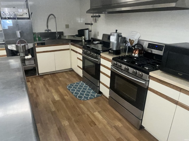 kitchen with dark wood-type flooring, gas stove, black microwave, and white cabinetry