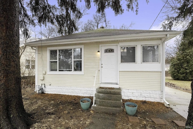 bungalow-style home with entry steps and a shingled roof