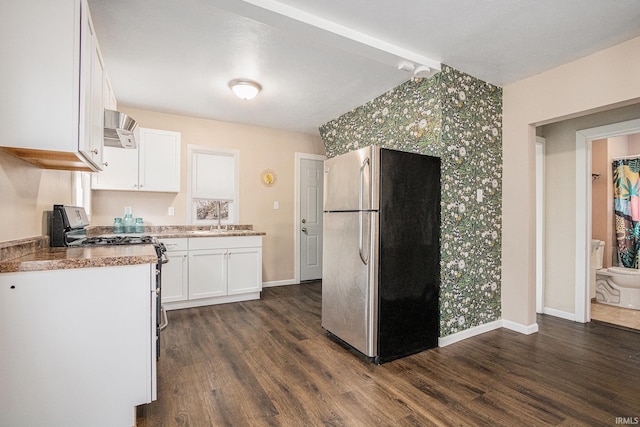 kitchen with appliances with stainless steel finishes, white cabinetry, dark wood finished floors, and baseboards