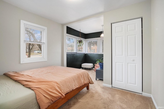 bedroom featuring light carpet, a closet, and baseboards