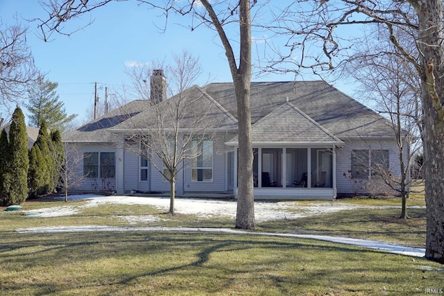 rear view of house featuring a yard, roof with shingles, a chimney, and a sunroom