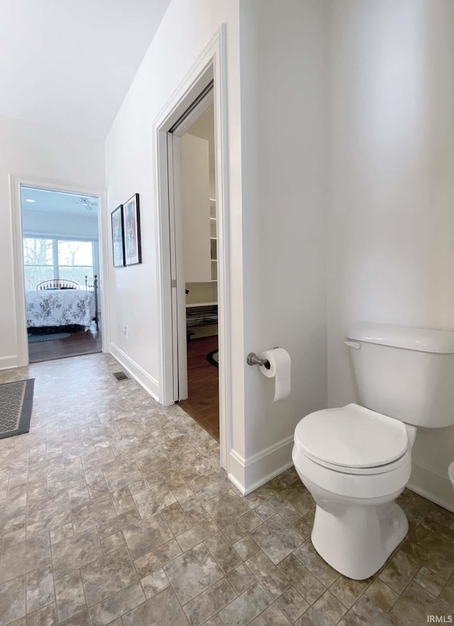 bathroom featuring ensuite bathroom, toilet, visible vents, baseboards, and stone finish flooring