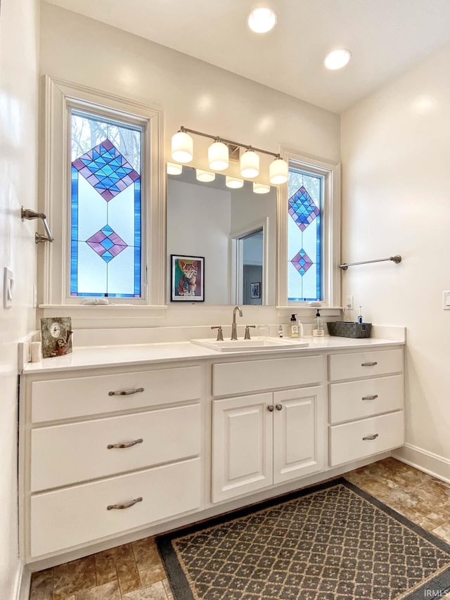 bathroom with baseboards, vanity, and recessed lighting