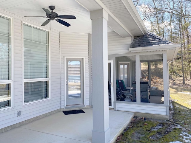 entrance to property featuring a ceiling fan, covered porch, and roof with shingles