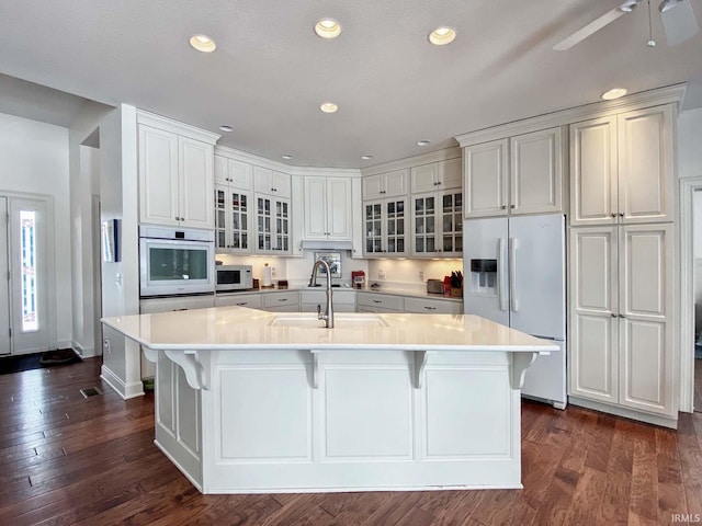 kitchen featuring recessed lighting, light countertops, dark wood-type flooring, a sink, and white appliances