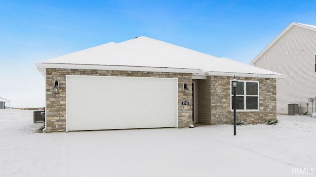 view of front facade with stone siding, an attached garage, and cooling unit