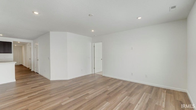 spare room featuring light wood-style floors, baseboards, visible vents, and recessed lighting