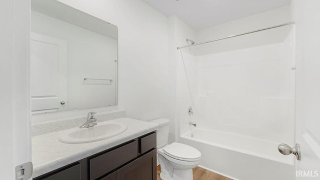 bathroom with wood finished floors, tub / shower combination, vanity, and toilet