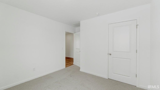 unfurnished bedroom with light colored carpet and baseboards