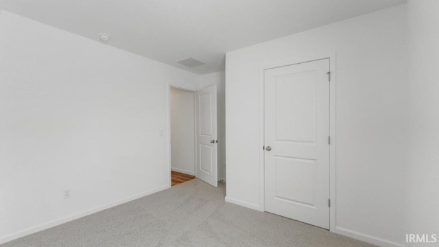 unfurnished bedroom with carpet flooring, visible vents, and baseboards