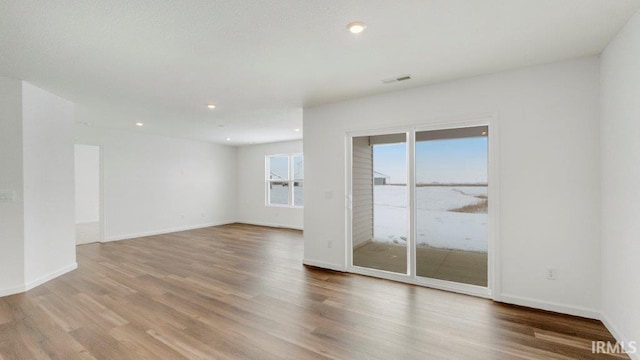 unfurnished room with baseboards, visible vents, wood finished floors, and recessed lighting