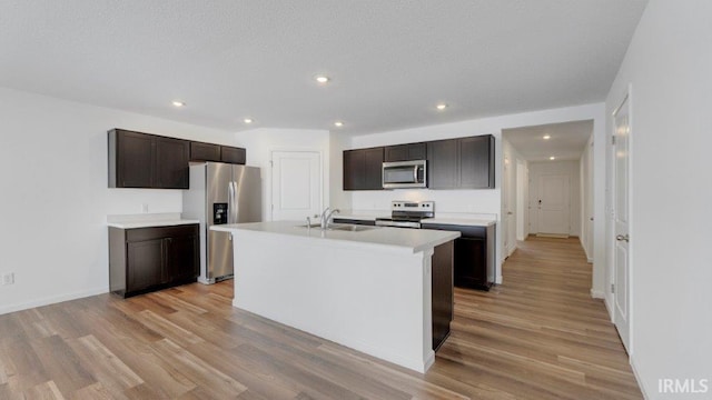 kitchen featuring stainless steel appliances, dark brown cabinets, light wood-type flooring, and light countertops