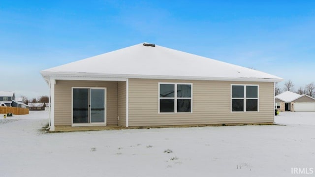 snow covered back of property with a detached garage