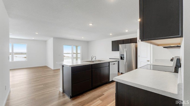 kitchen featuring a kitchen island with sink, white dishwasher, a sink, range with electric cooktop, and stainless steel fridge