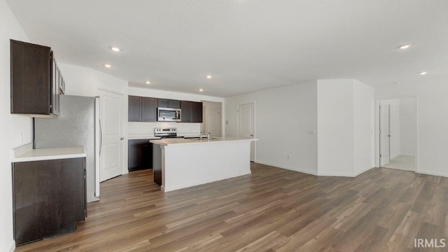 kitchen featuring dark brown cabinets, stainless steel microwave, dark wood finished floors, and a sink